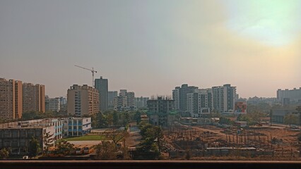 View from an building showing the construction work going on, a nearby school with buses, developments of the city.