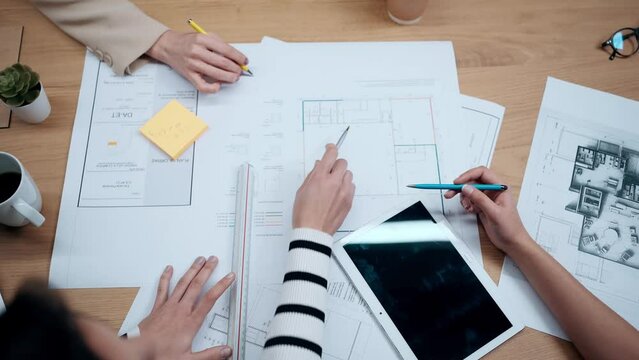 Video of close up of hands of architects working with blueprints of their new design business in the office.