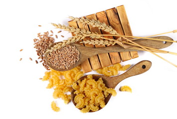 Pasta cornetti creste macaroni pile in wooden spoon and ears wheat isolated on white, top view 