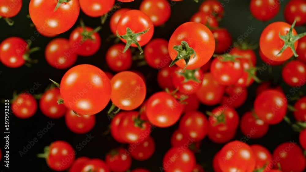 Poster super slow motion of cherry tomatoes flying on black background. filmed on high speed cinema camera,