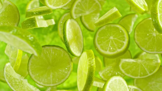 Super slow motion of flying lime slices on green background. Filmed on high speed cinema camera, 1000 fps. Camera placed on high speed cine bot, tracking the object. Speed ramp effect.