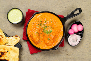 Top view of butter chicken served with naan and mint chutney