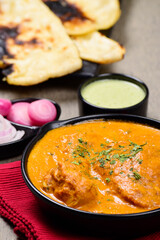 Butter chicken closeup with naan and mint chutney