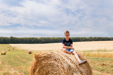 Children on round bales, mowed wheat, bales of wheat, children in Ukraine, wheat field, children in a wheat field with a beautiful sky, bales
