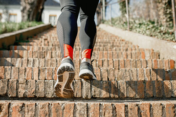 legs of a woman running athlete up the stairs, big load, outdoor running, healthy lifestyle, well-being of active people