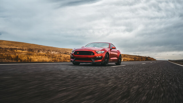 LA, California - April 30, 2023 Ford mustang red car driving on highway. American muscle car on the highway