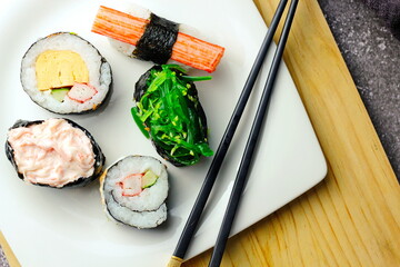 Sushi served in a white plate with sauce.