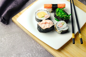 Sushi served in a white plate with sauce.