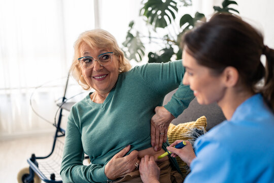 Senior Woman In Retirement Receiving Her Daily Insulin Injection Therapy For Diabetes Treatment At Home. Nurse Injecting Insulin With Pen To Elderly Female Patient, Providing Home Care Services.