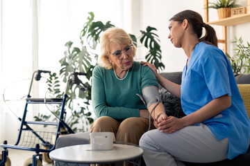 Female homecare professional consoling worried senior woman while measuring blood pressure during home visit. Elderly woman upset about too high blood pressure. Nurse caring for older woman at home.