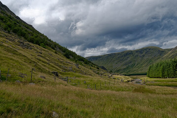 Fototapeta na wymiar Looking up the Valley from the Footbridge crossing the River South Esk with dark clouds threatening rain on a Summers day in August.