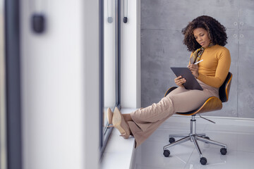 Serious african-american businesswoman using digital tablet in office