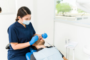 Woman dentist treating a man for teeth cavities