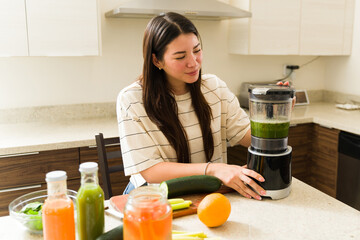 Beautiful vegetarian woman making an organic vegetable smoothie