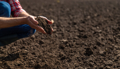 Male farmer in the field checks the soil. Selective focus.