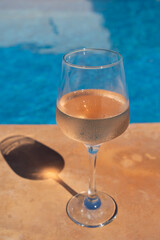 rose wine by the blue swimming pool wine glass filled with alcoholic drink for summer and recreation