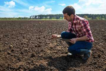 Male farmer in the field checks the soil. Selective focus.