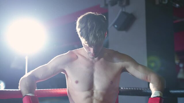 The boxers are resting and taking deep breaths in the corner of the boxing ring before gathering their strength and fighting again.
