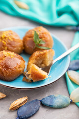 Traditional turkish dessert sekerpare with almonds and honey on gray concrete, side view, selective focus.