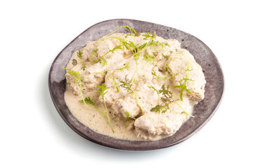 Stewed chicken fillets with coconut milk sauce isolated on white. side view, close up.
