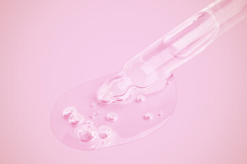 A flowing clear gel from a pipette. A lot of flowing gel in a big drop. With bubbles. On a pink background.