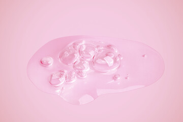 A drop of transparent gel smeared on a pink background.