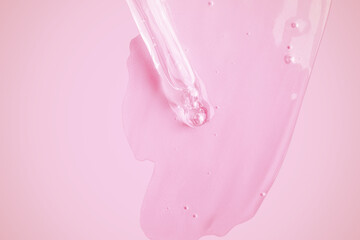 A flowing clear gel from a pipette. Lots of flowing gel smeared on the background. With bubbles. On a pink background.