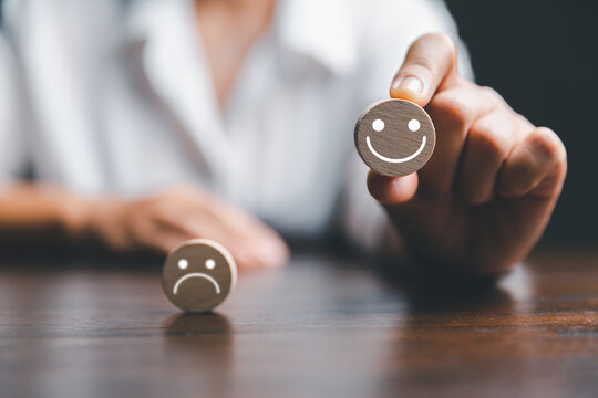 Customer experience with customer service and satisfaction concept. Woman hand picked the happy face smile face icon on wooden cube with copy space