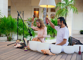 beautiful girl and mexican chaman playing tibetan bowls in a meditation ceremony