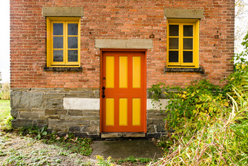 Colorful yellow and red wooden door with windows on brick facade