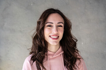 Portrait of happy caucasian woman - Confident and smiling young  woman with long wavy brown hair having fun while posing in front of the camera - Young generations and gen z concept - obrazy, fototapety, plakaty