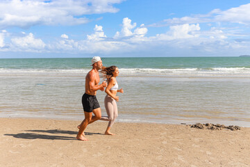 Fototapeta premium Two buddy runners jogging outdoor on summer tropical island beach with blue sea, couple doing exercise outdoor, sport man and woman jogger athlete doing and training workout, lover morning workout.