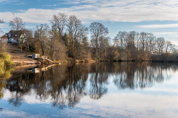 Beautiful landscape of a lake and private house, reflection in the water, autumn nature. 