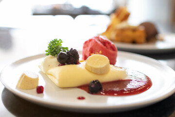 Soft crape with sorbet ice cream with berry juicy sauce and banana sliced with crumble.