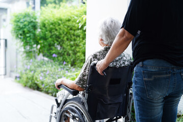 Caregiver help Asian elderly woman disability patient sitting on wheelchair in hospital, medical...