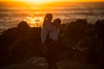 Fototapeta premium A young couple in love having fun on the ocean during a golden sunset. .