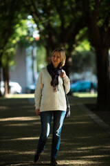 A woman walks in a shady green park.