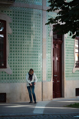 A woman on the street outside a house in Porto, Portugal.