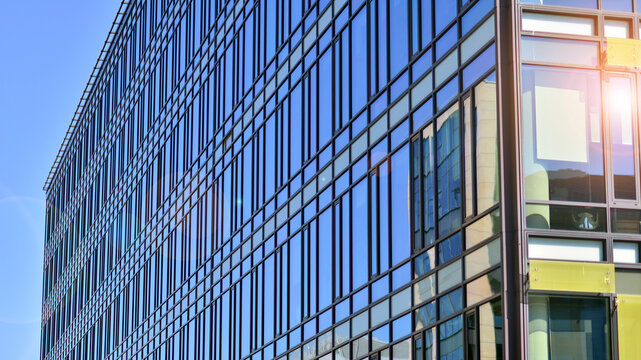 Abstract fragment of contemporary architecture, walls made of glass and concrete. Abstract closeup of the glass-clad facade of a modern building covered in reflective plate glass.
