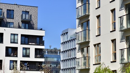 Obraz premium Modern apartment buildings on a sunny day with a blue sky. Facade of a modern apartment building. Contemporary residential building exterior in the daylight. 