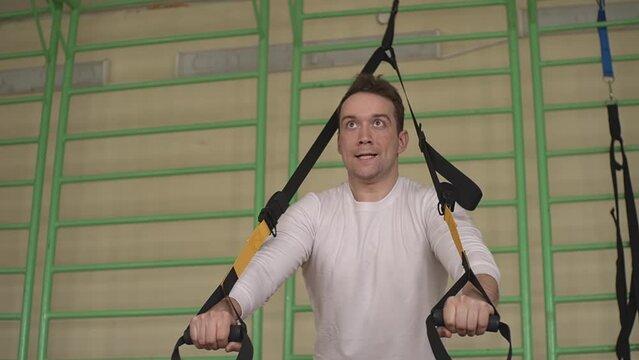 a man in a white t-shirt .training with fitness loops in the gym. closeup.slow motion video. High quality Full HD video recording Generative AI