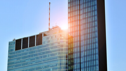 Windows of a modern glass building. Looking up at the commercial buildings in downtown. Modern office building against blue sky. 