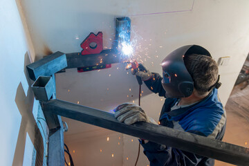 An experienced man welding a seam on a spiral staircase at a construction site.
