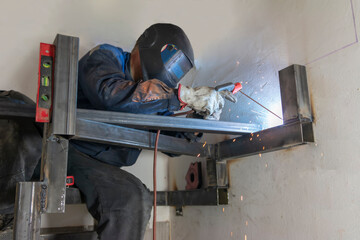 An experienced man welding a seam on a spiral staircase at a construction site.