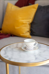 close-up of a coffee or tea mug with a saucer on a marble table near the sofa