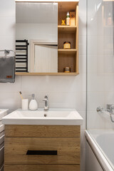 Fototapeta na wymiar part of the bathroom interior, a sink, a round mirror, a cabinet