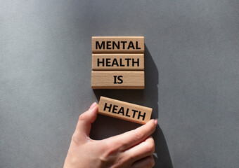 Mental Health symbol. Wooden blocks with words Mental Health is Health. Beautiful grey background. Doctor hand. Medical and Health concept. Copy space.