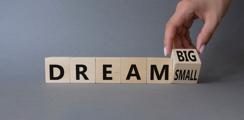 Dream Big vs Small symbol. Businessman Hand turns cubes and changes words Dream Small to Dream Big. Beautiful grey background. Business and Dream concept. Copy space