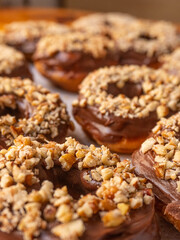 Chocolate donuts with pieces of nuts and background with more donuts