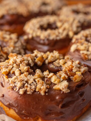 Chocolate donuts with pieces of nuts and background with more donuts